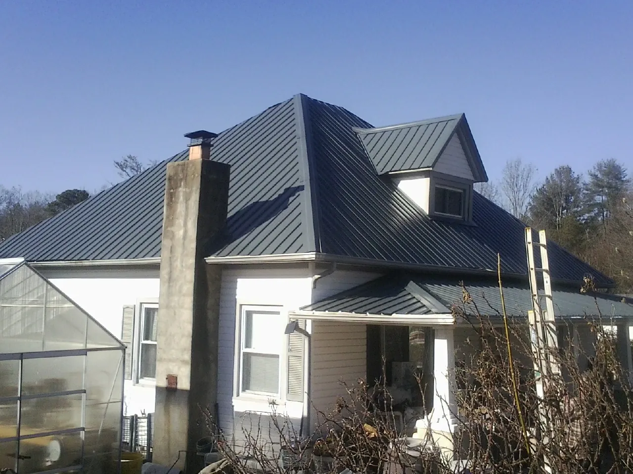 Dark blue standing seam metal roof on a white farmhouse with dormer — Slate & Tile Roof Repair by Roofing Brothers in Little York