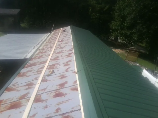 Old rusted panels beside newly installed green metal roofing — Wind Damage Roof Repair by Roofing Brothers in Little York