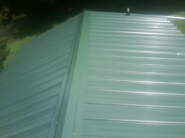 New green metal panels meeting at the ridge of a roof — Flat Roof Repair work by our crew in Little York
