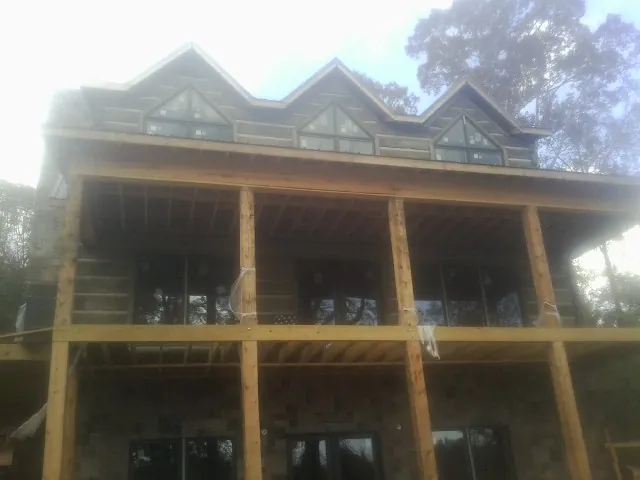 Dormers and porch framing on a large log home under construction — Roof Coating work by our crew in Little York