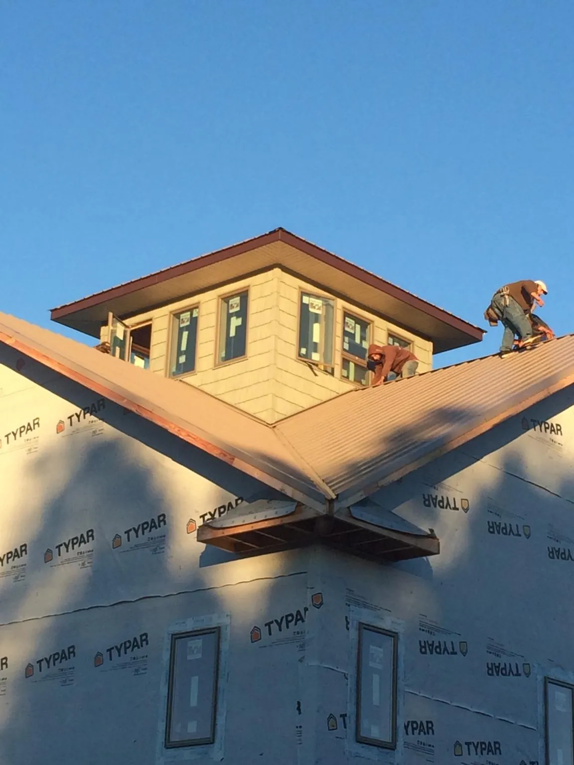 Roofers working around a rooftop cupola on a new metal roof at sunset — Roof Waterproofing in Little York by Roofing Brothers